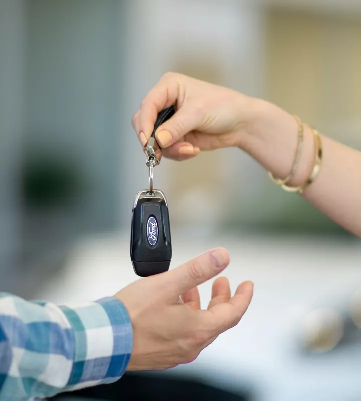 Uma pessoa entrega a chave do carro a outra